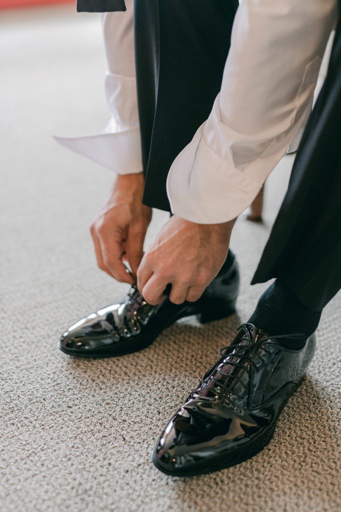Groom tieing shoes for the wedding